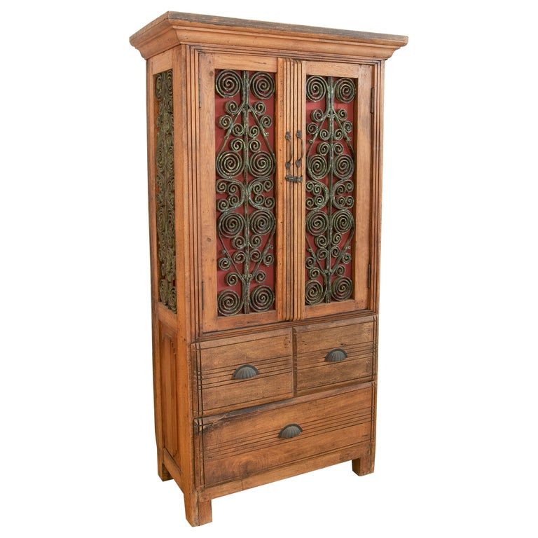 Armario de madera con puertas decoradas con hierro y tres cajones