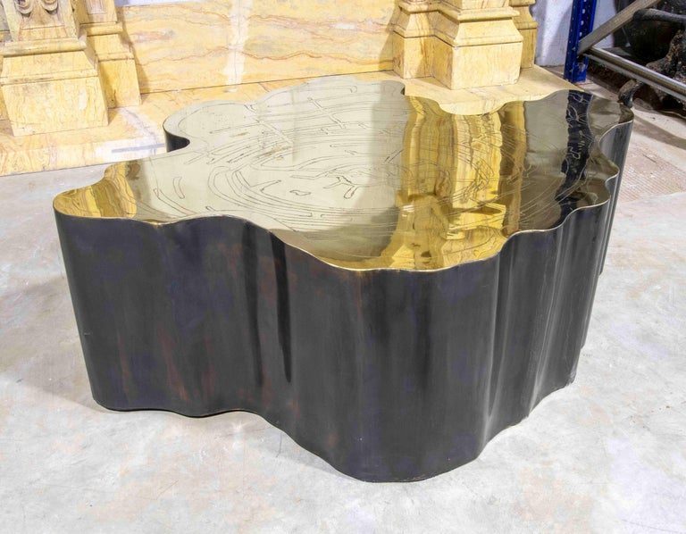Mesa de centro escultural de metal con tapa de latón grabado