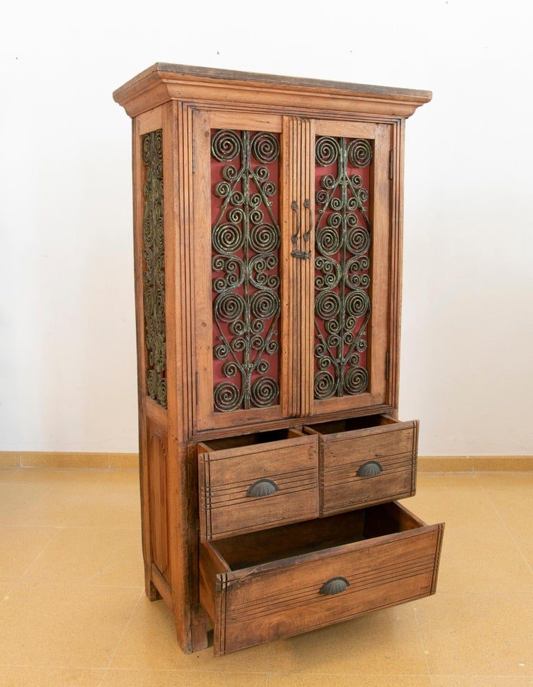 Armario de madera con puertas decoradas con hierro y tres cajones