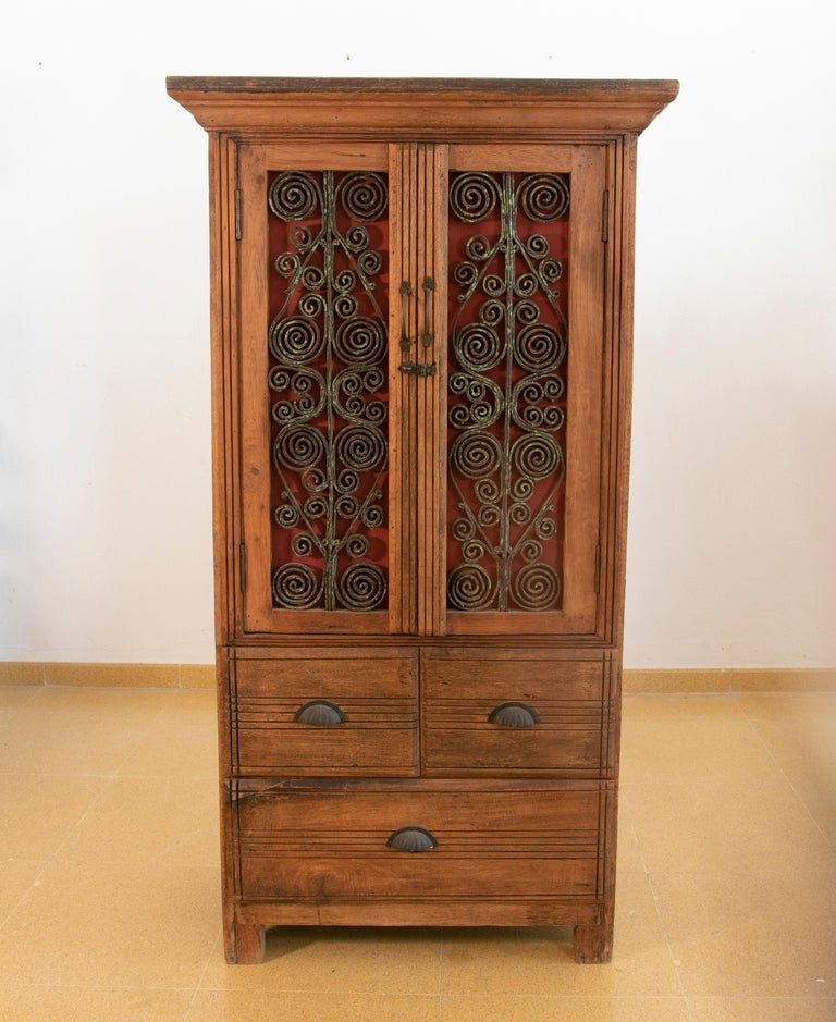 Armario de madera con puertas decoradas con hierro y tres cajones