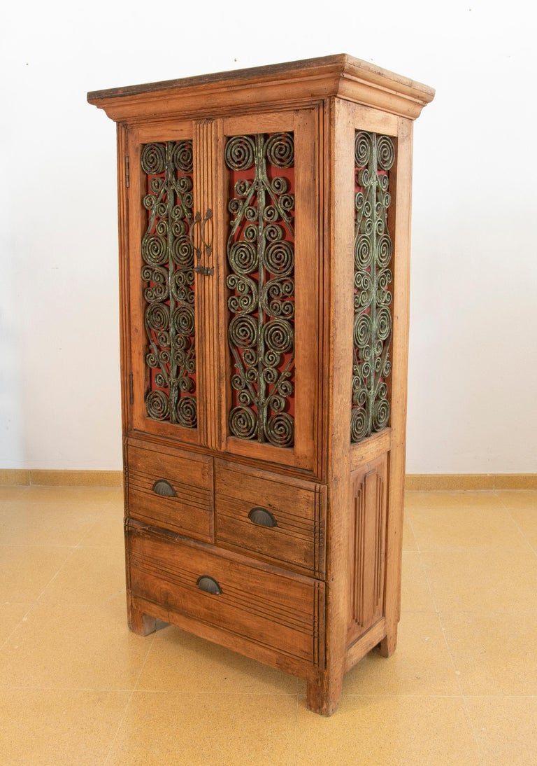 Armario de madera con puertas decoradas con hierro y tres cajones