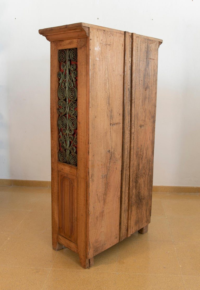 Armario de madera con puertas decoradas con hierro y tres cajones