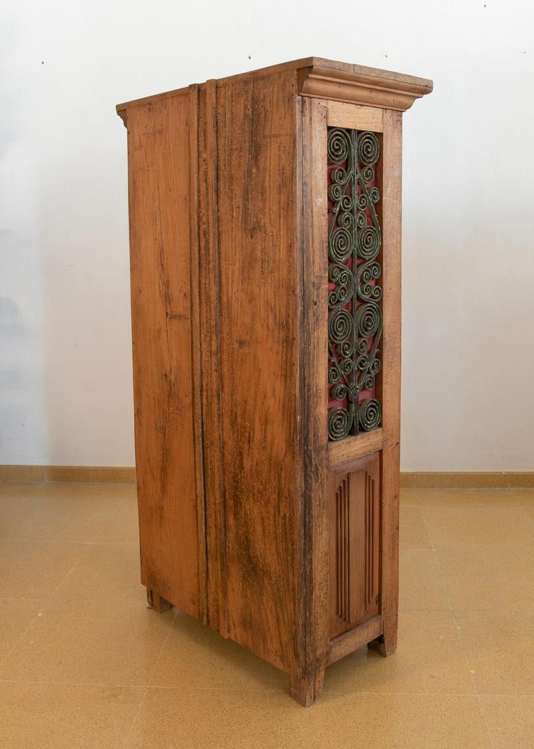 Armario de madera con puertas decoradas con hierro y tres cajones