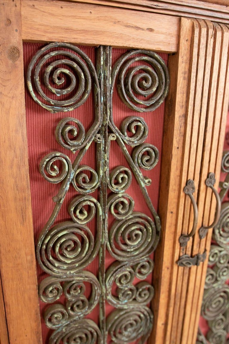 Armario de madera con puertas decoradas con hierro y tres cajones