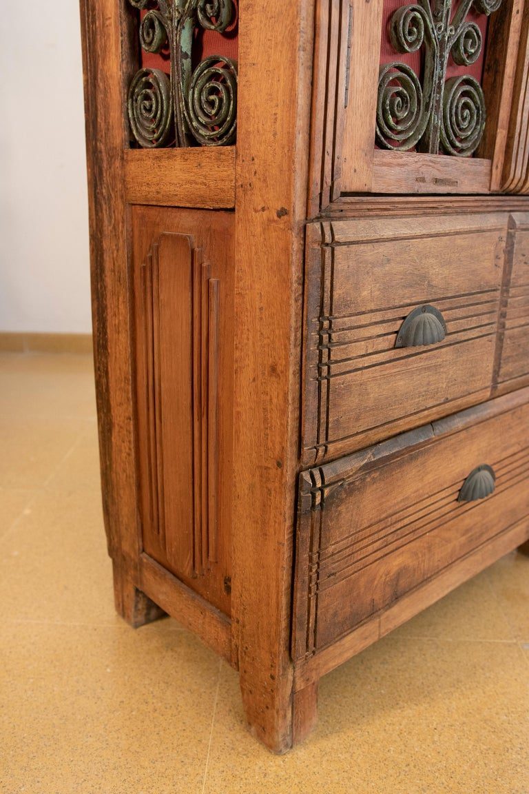 Armario de madera con puertas decoradas con hierro y tres cajones