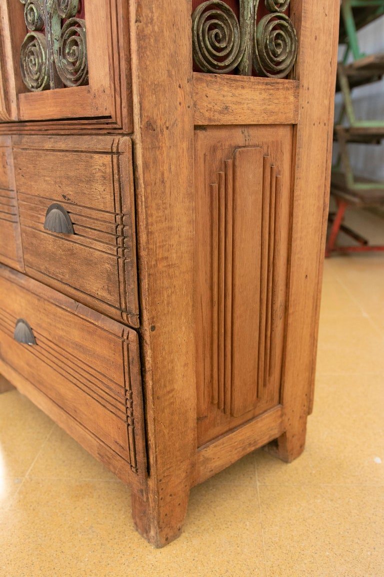 Armario de madera con puertas decoradas con hierro y tres cajones
