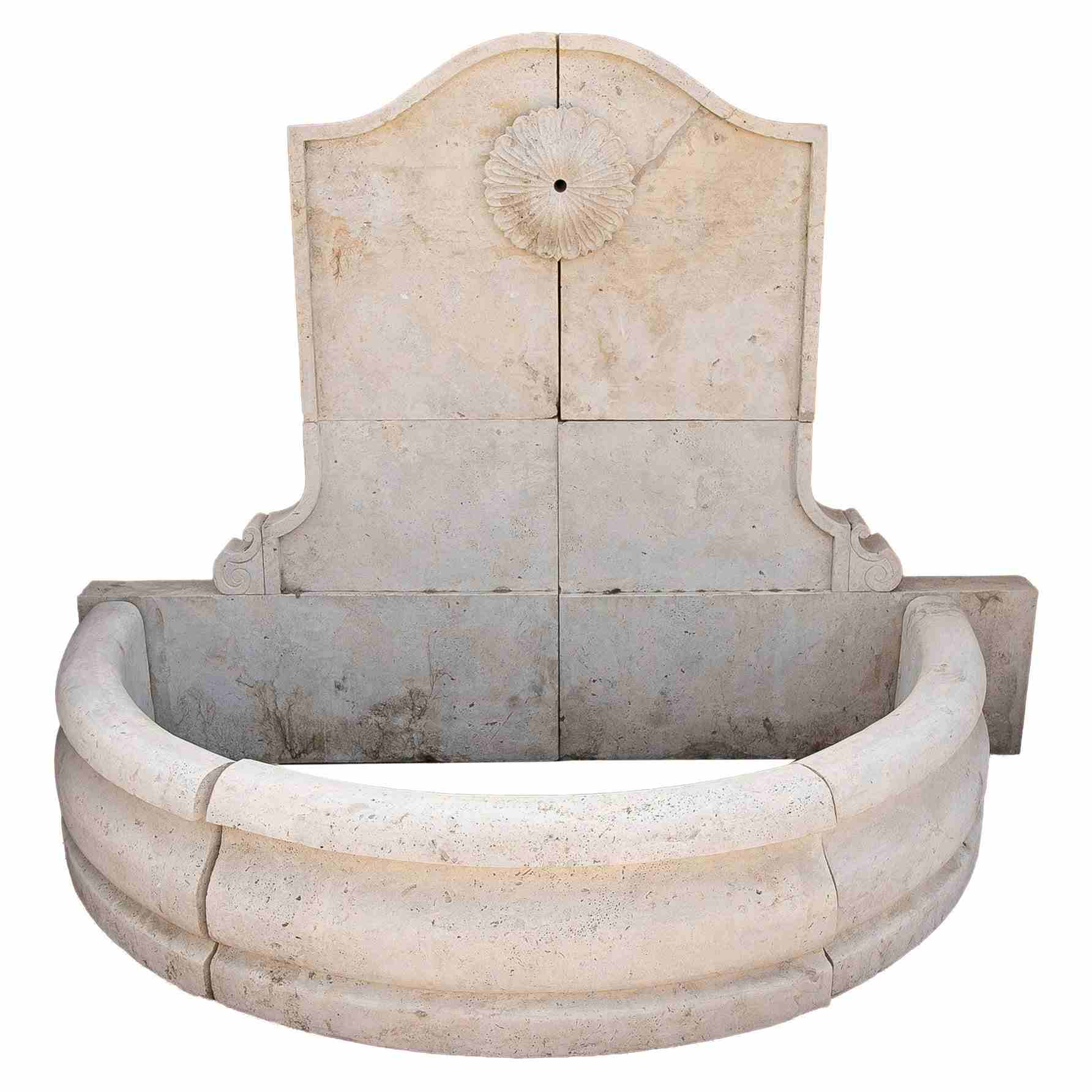 Fuente de pared de mármol tallado con una pileta semicircular y una roseta clásica.